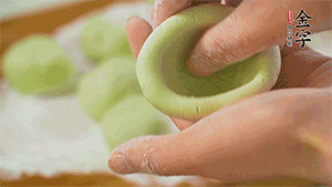 將均分的艾草面團(tuán)搓成圓，挖一個窩，放入餡心，再搓成圓。