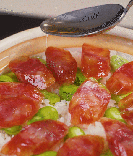 大米出現(xiàn)小孔時(shí)開(kāi)蓋放香腸，往鍋邊淋入少許油，再燜煮8~10分鐘左右。